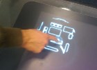 a hand touching a large touch screen